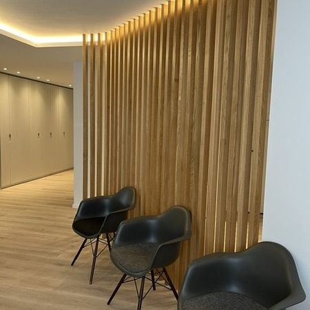 Moderner Wartebereich mit Holzverkleidung und stilvollen Stühlen, das eine einladende Arbeitsatmosphäre schafft.