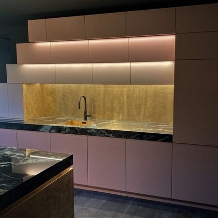 Eine moderne Küche mit rosa Schränken und marmorierten Arbeitsplatten.