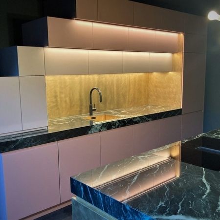 Eine moderne Küche mit Marmorarbeitsplatten und rosa Schränken, die einen eleganten und stilvollen Look bietet.