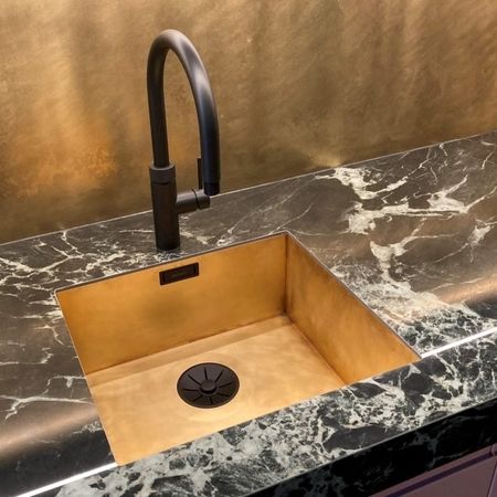 Ein goldener Waschbecken in einer marmorierten Arbeitsplatte.