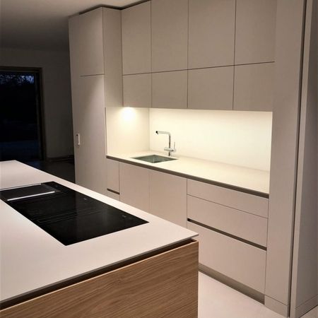 Moderne Küche mit weißen Schränken und Arbeitsflächen, die ein helles und sauberes Ambiente schaffen.