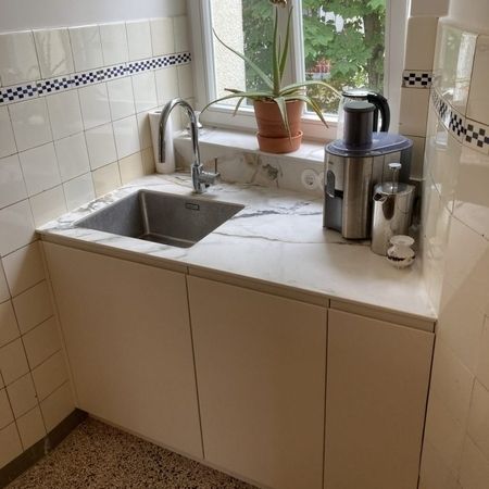 Eine Küche mit einem Waschbecken und einem Fenster, das Tageslicht hereinlässt.