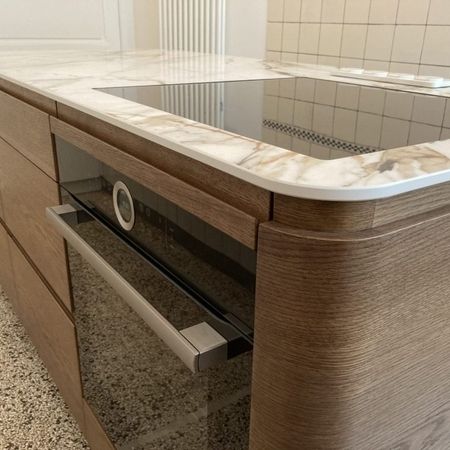 Eine moderne Küche mit einer marmorierten Arbeitsplatte und einem Herd.