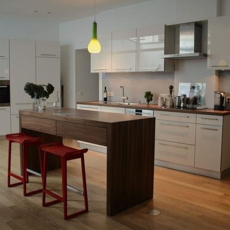 Eine moderne Küche mit einer Bar und einem Esstisch, die einladend und funktional gestaltet ist.