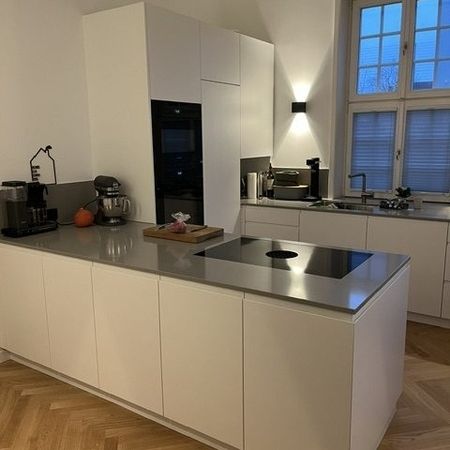 Eine moderne Küche mit weißen Schränken und einem warmen Holzboden.